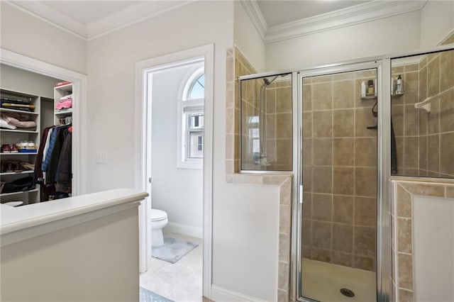 bathroom featuring tile patterned floors, crown molding, a shower with shower door, and toilet