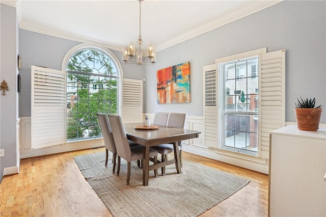 dining area featuring crown molding, a wealth of natural light, light wood-type flooring, and a chandelier