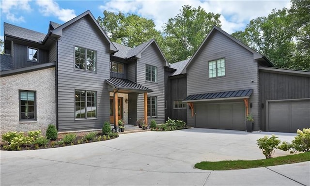 view of front of house featuring metal roof, an attached garage, brick siding, driveway, and a standing seam roof