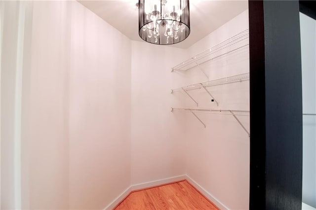 spacious closet with wood-type flooring and a notable chandelier