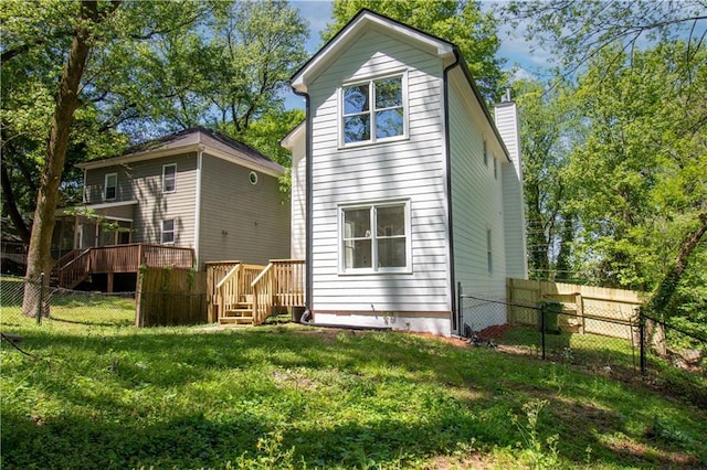 rear view of property featuring a yard, fence, a chimney, and a wooden deck