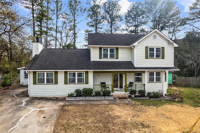 traditional-style home with driveway, covered porch, a chimney, and fence