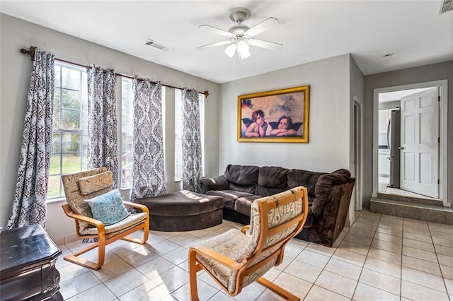 living room with ceiling fan, visible vents, and light tile patterned flooring