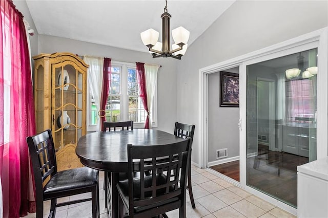 dining room featuring a notable chandelier, lofted ceiling, visible vents, light tile patterned flooring, and baseboards