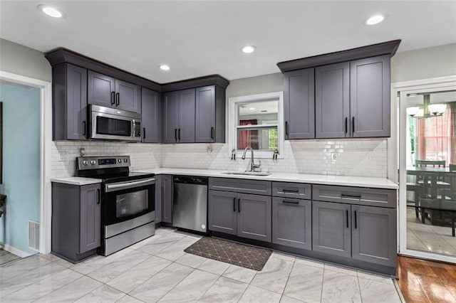 kitchen with visible vents, decorative backsplash, appliances with stainless steel finishes, light countertops, and a sink