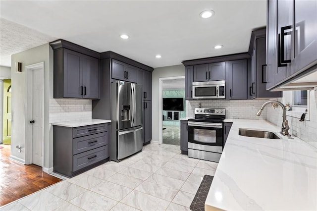 kitchen featuring light stone counters, recessed lighting, a sink, baseboards, and appliances with stainless steel finishes