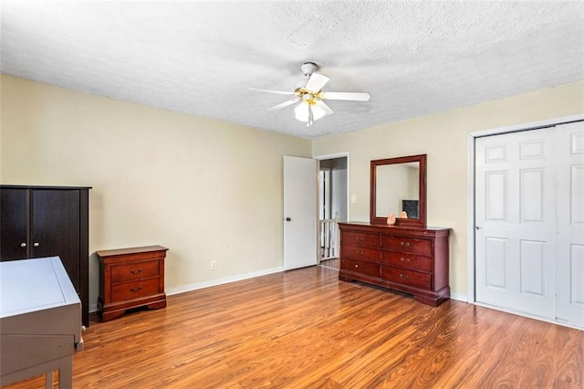 bedroom featuring a textured ceiling, ceiling fan, wood finished floors, and baseboards