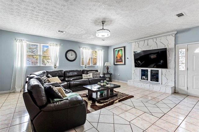 living room with light tile patterned floors, a textured ceiling, visible vents, and baseboards