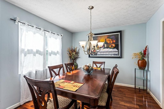 dining space featuring a notable chandelier, a textured ceiling, baseboards, and wood finished floors