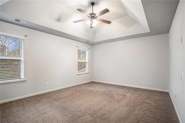 spare room with a tray ceiling, ceiling fan, and carpet floors