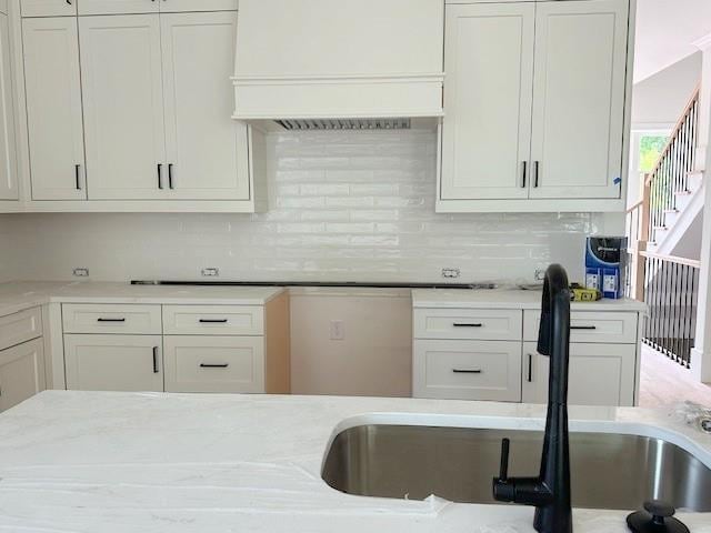 001 White St Unit 1, Marietta, GA 30060 - kitchen with a sink, custom range hood, white cabinetry, backsplash, and light stone counters