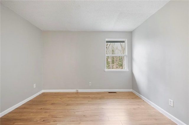 unfurnished room featuring a textured ceiling, baseboards, and light wood finished floors