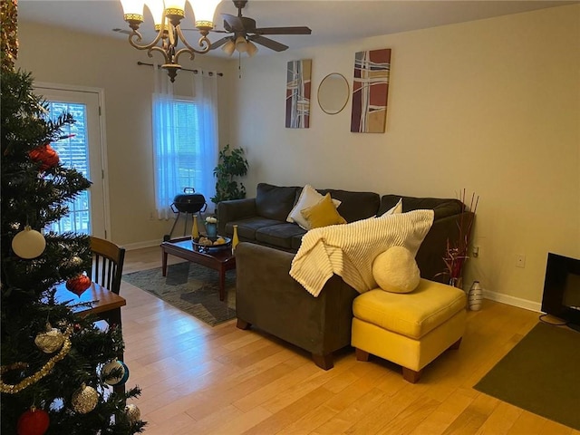 living room with light hardwood / wood-style flooring and ceiling fan with notable chandelier