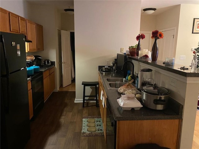 kitchen featuring kitchen peninsula, dark hardwood / wood-style flooring, sink, and black appliances