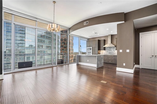 unfurnished living room featuring dark wood-type flooring, baseboards, visible vents, and expansive windows