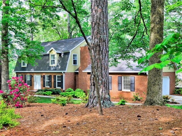 view of front of property featuring brick siding, a shingled roof, and an attached garage