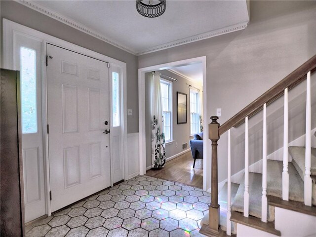 entryway featuring crown molding, visible vents, and stairway