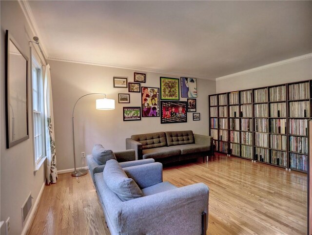 living room with baseboards, visible vents, ornamental molding, and wood finished floors