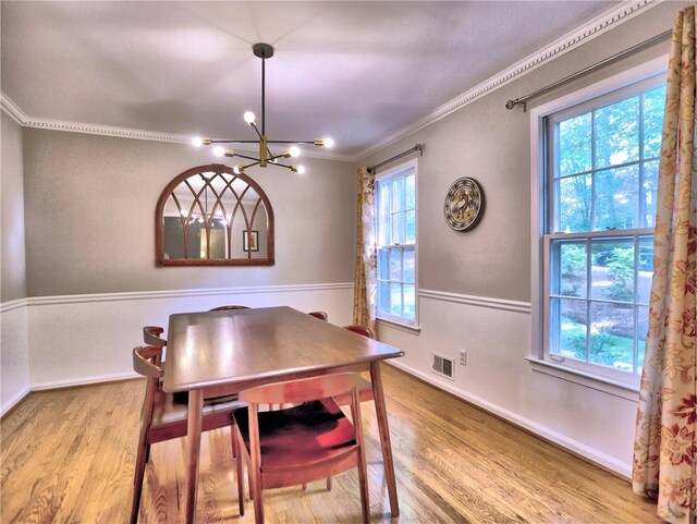dining room featuring visible vents, ornamental molding, wood finished floors, baseboards, and a notable chandelier