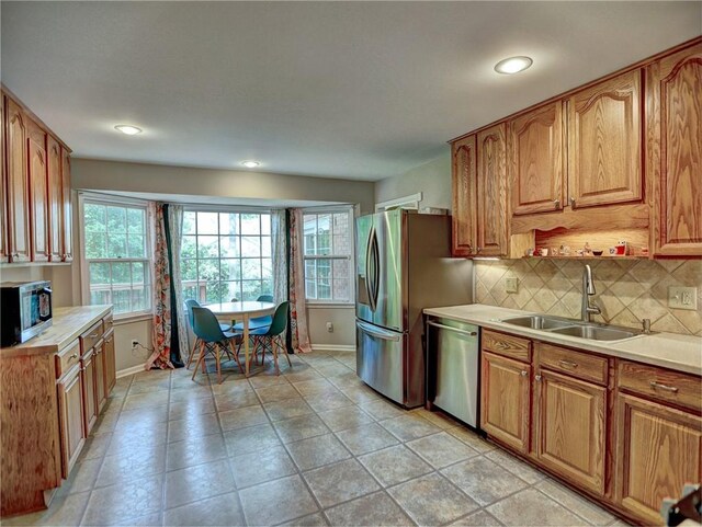 kitchen with baseboards, a sink, backsplash, and stainless steel appliances