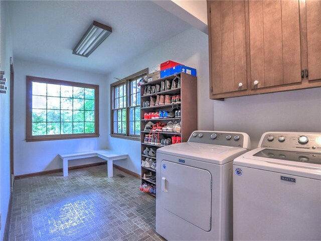 washroom with cabinet space, baseboards, brick patterned floor, and washer and dryer