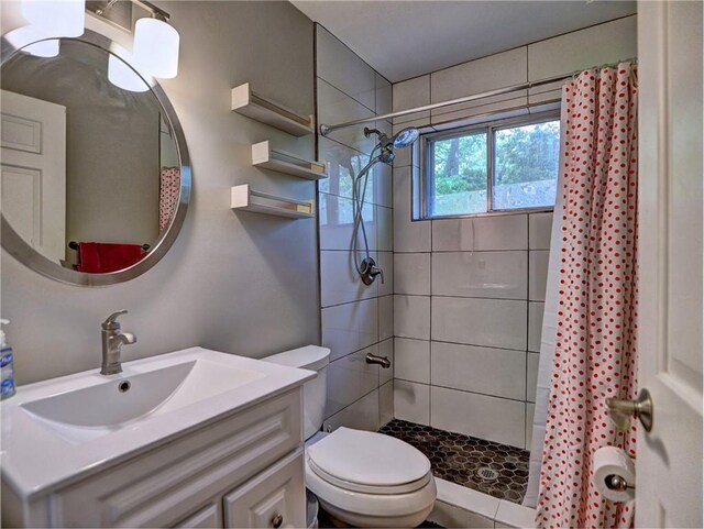 bathroom featuring vanity, toilet, and tiled shower