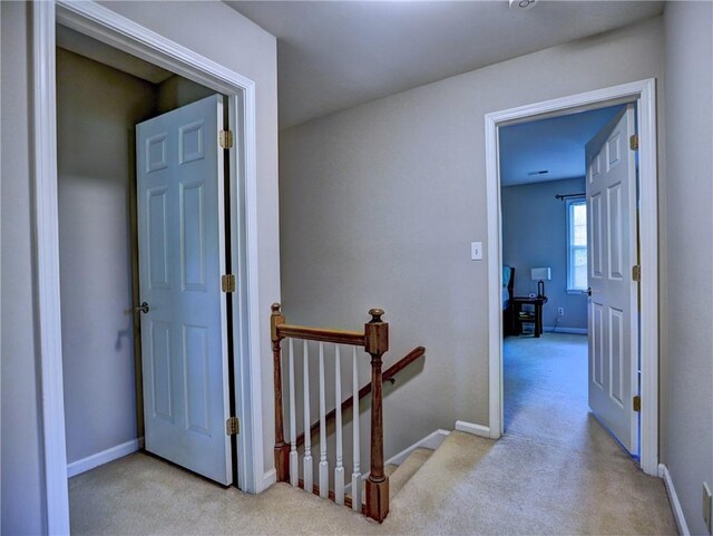hall featuring baseboards, an upstairs landing, and carpet