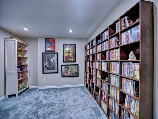 living area featuring carpet floors, recessed lighting, wall of books, and baseboards