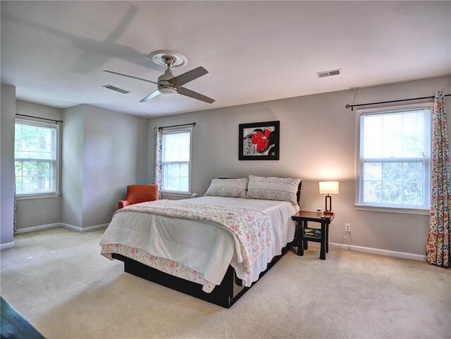 bedroom featuring light colored carpet, baseboards, visible vents, and a ceiling fan
