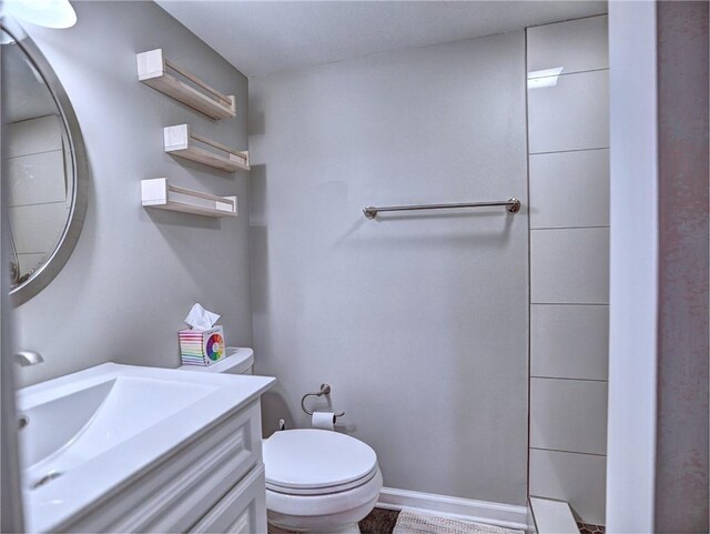 full bathroom featuring vanity, baseboards, walk in shower, and toilet