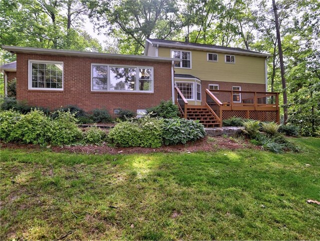 back of property featuring a lawn, brick siding, and a wooden deck