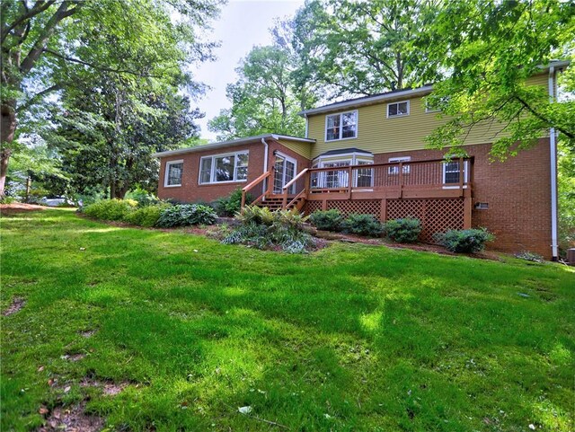 rear view of property featuring brick siding, a yard, and a deck