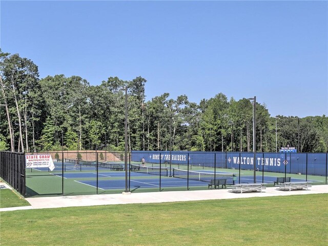 view of tennis court with fence and a yard