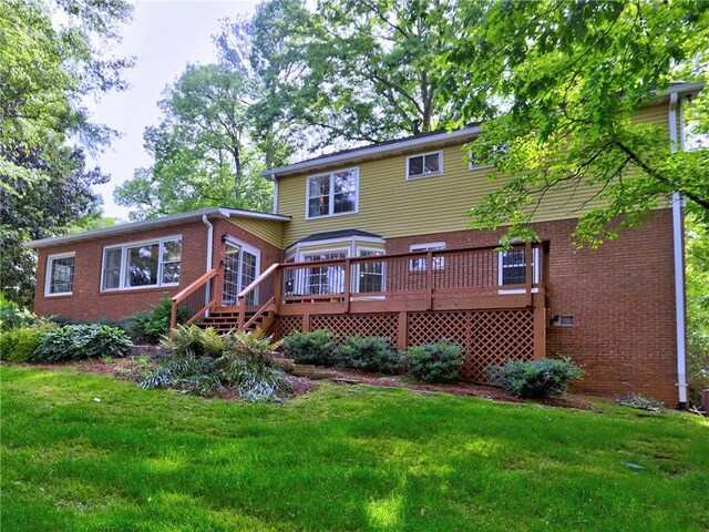 rear view of house featuring a wooden deck, a yard, and brick siding