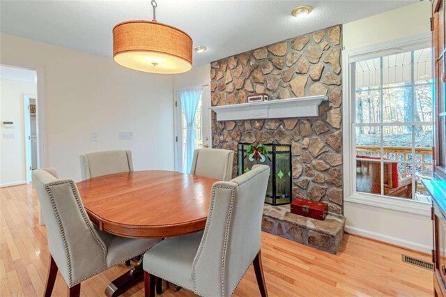 dining area with hardwood / wood-style flooring and a stone fireplace