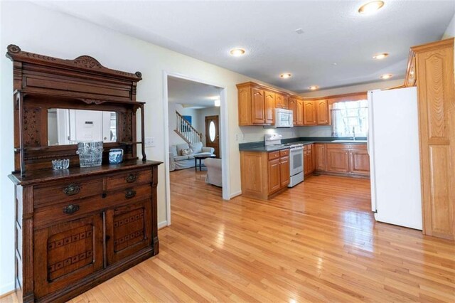 kitchen with light wood-type flooring, white appliances, and sink