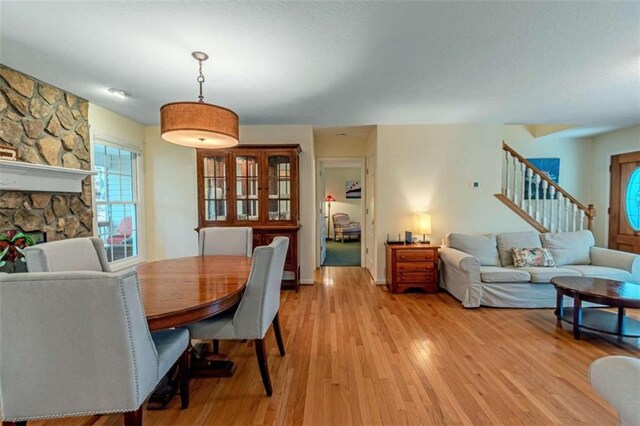 dining room with light wood-type flooring and a fireplace