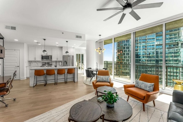 1080 Peachtree St NE Unit 1909, Atlanta, GA 30309 - living room featuring visible vents, light wood-style flooring, floor to ceiling windows, and ceiling fan with notable chandelier