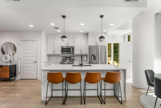 1080 Peachtree St NE Unit 1909, Atlanta, GA 30309 - kitchen with an island with sink, a sink, stainless steel appliances, a breakfast bar area, and decorative backsplash