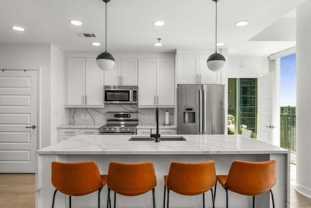 1080 Peachtree St NE Unit 1909, Atlanta, GA 30309 - kitchen with a breakfast bar area, visible vents, a sink, decorative backsplash, and appliances with stainless steel finishes