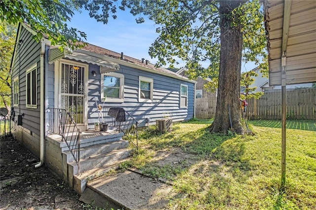 view of front of property with a front lawn, cooling unit, and fence