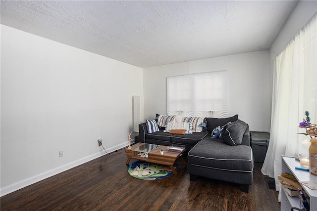 living area featuring a textured ceiling, baseboards, and wood finished floors