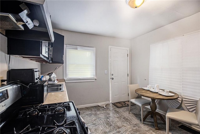 kitchen featuring light countertops, stainless steel gas stove, a sink, and baseboards