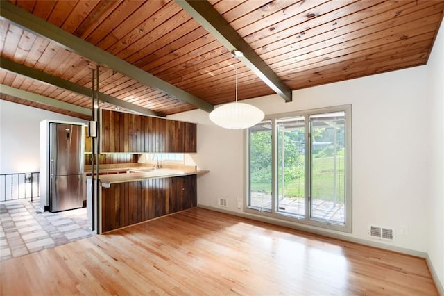 3861 Foxford Dr, Atlanta, GA 30340 - kitchen featuring freestanding refrigerator, a peninsula, wooden ceiling, brown cabinetry, and decorative light fixtures