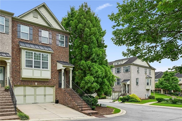 townhome / multi-family property featuring an attached garage, brick siding, a residential view, concrete driveway, and a standing seam roof