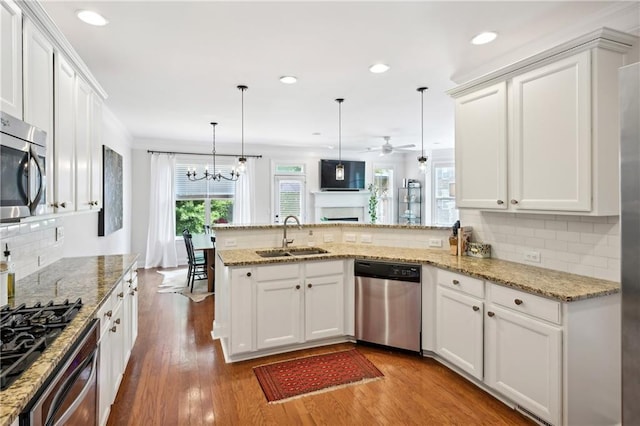 kitchen with a peninsula, a sink, white cabinetry, appliances with stainless steel finishes, and decorative backsplash