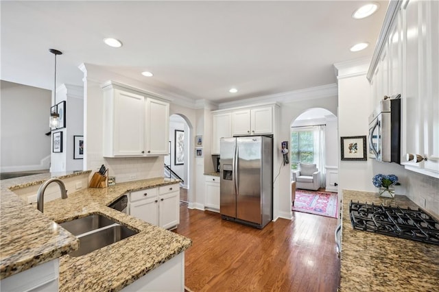 kitchen featuring a sink, stainless steel appliances, arched walkways, and light stone countertops