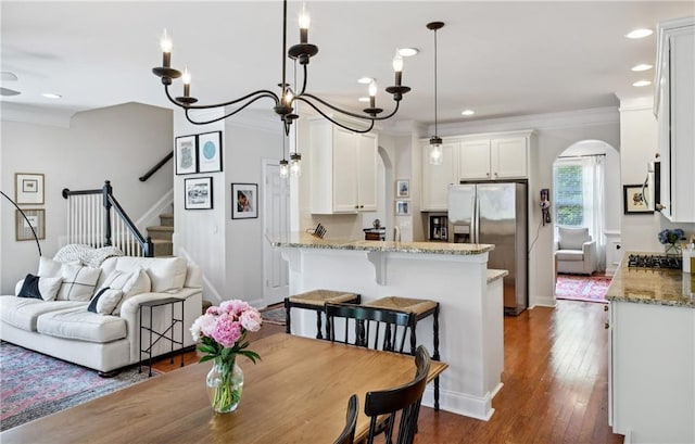 dining area with crown molding, dark wood finished floors, arched walkways, and recessed lighting