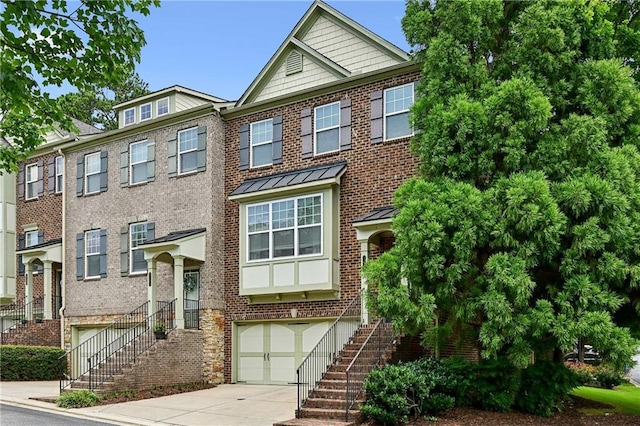 multi unit property featuring driveway, stairway, brick siding, and a garage