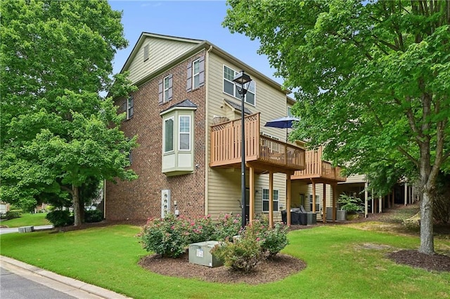back of property featuring a wooden deck, brick siding, and a lawn